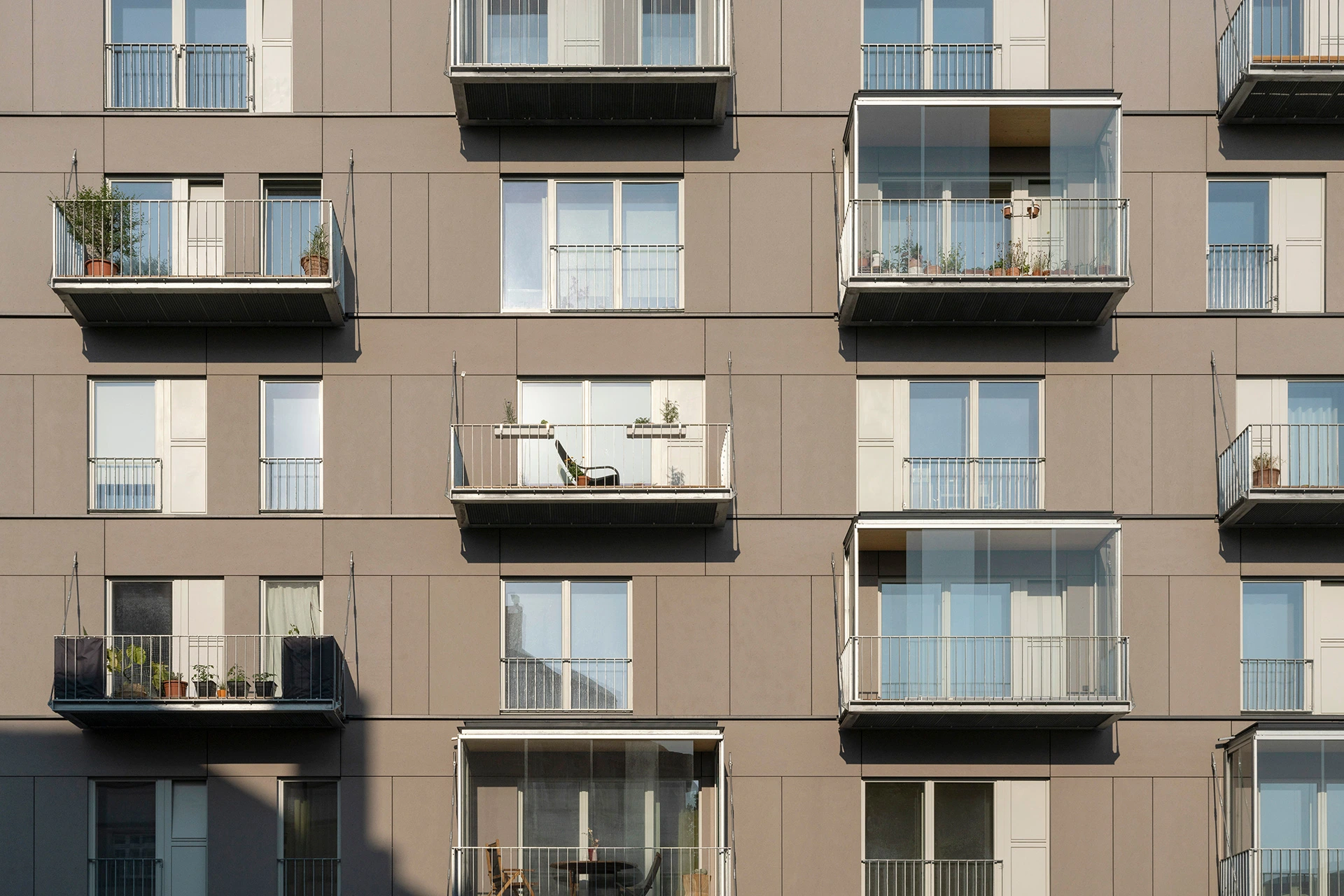 Graue Plattenfassade mit Hängebalkonen bei dem Holzhaus Linse