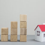 small house model stack increasing wooden block grey backdrop