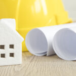 toy house near blueprints helmet